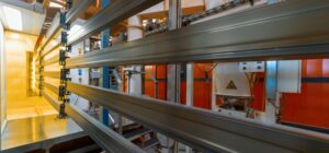 Aluminiowe profile na linii produkcyjnej w lakierni przemysłowej - lakierowanie proszkowe aluminium