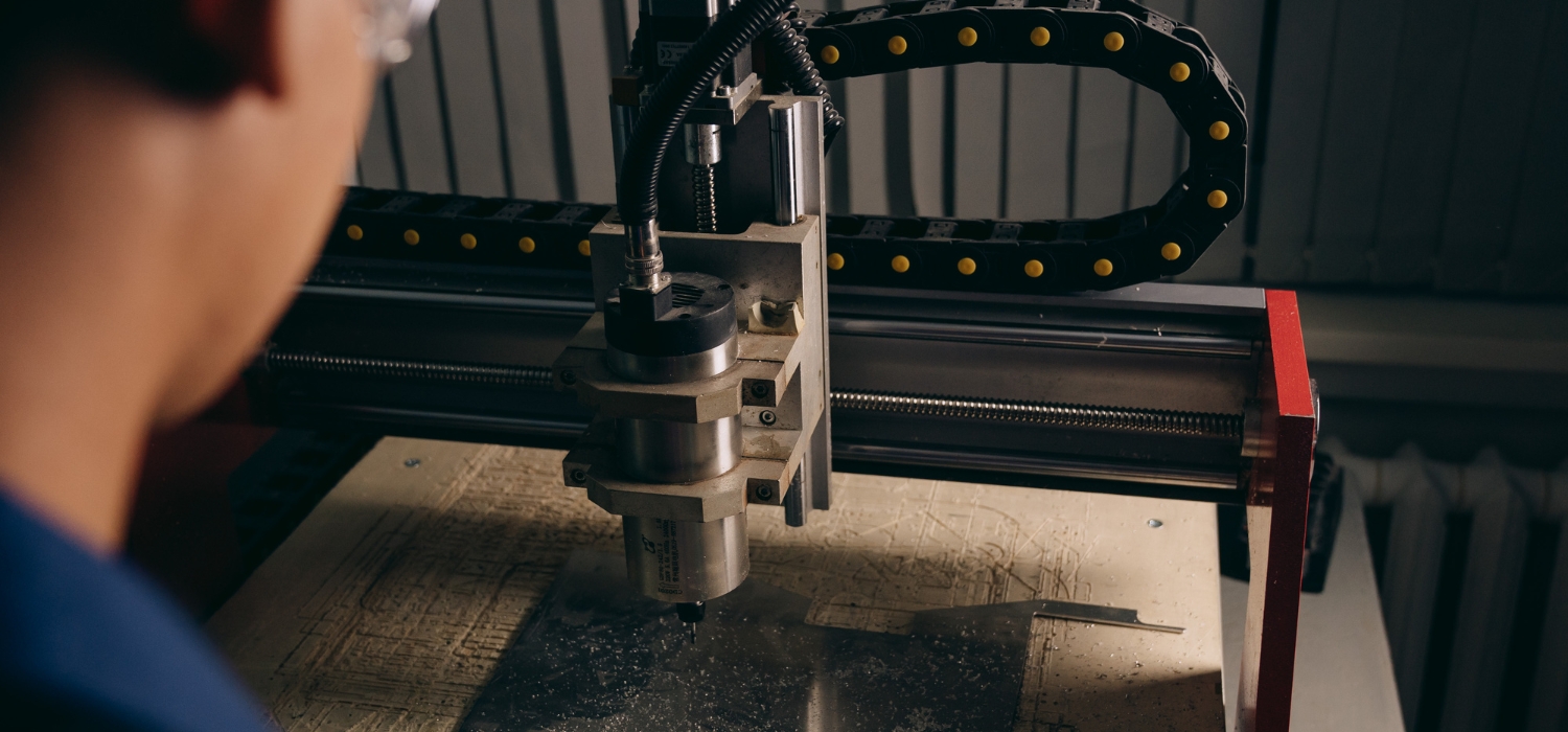 Pracownik obserwujący frezarkę CNC podczas obróbki aluminium